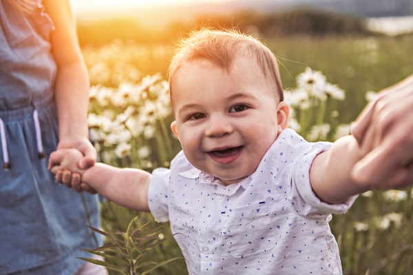 Toddler walking holding hands with off screen adults